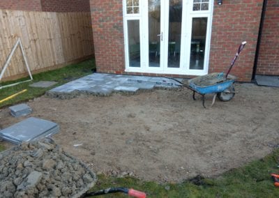Photo of a garden patio during landscaping, grass dug and wheelbarrow full of cement
