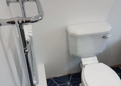 Photo of a bathroom with a white toilet and chrome and white radiator