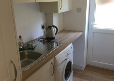 Photo of a kitchen utility room, kettle, sink and washing machine present
