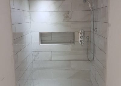 Shower with wall mounted shower head, a recess pocket and marble effect tiles