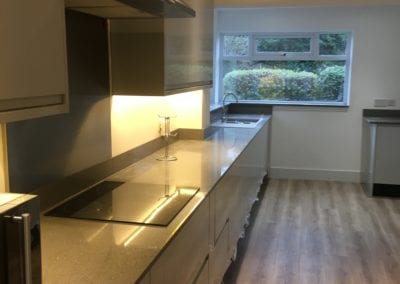 Light grey gloss kitchen with grey granite worktop and wooden flooring